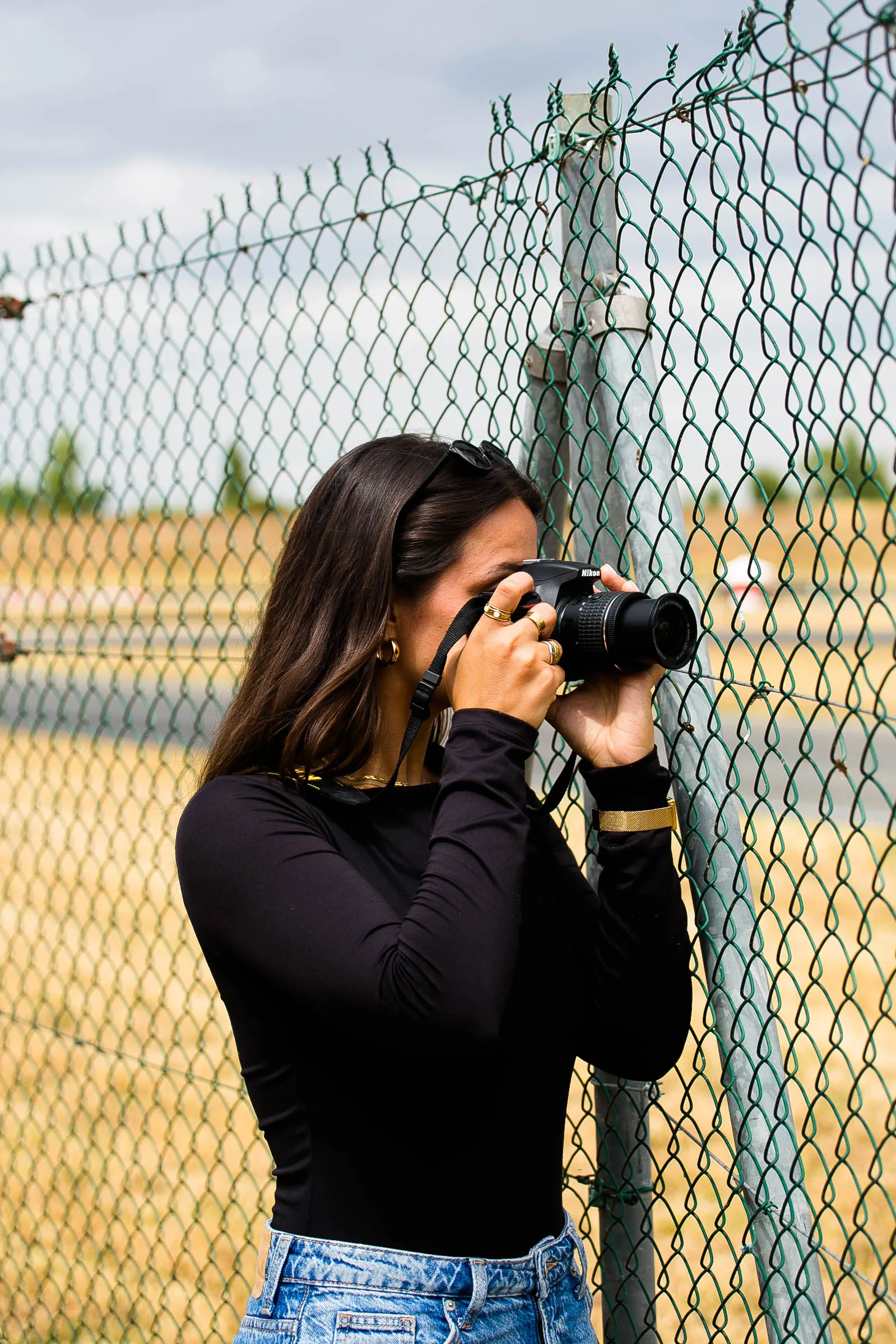Jeune femme photographiant à travers un grillage